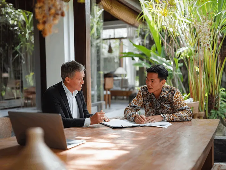 PT PMA director reviewing pension tax documents in Bali office with legal advisor explaining VAT and income rules